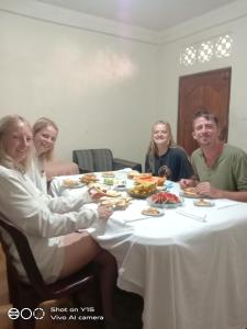 un grupo de personas sentadas alrededor de una mesa comiendo comida en Trinish homestay en Hatton