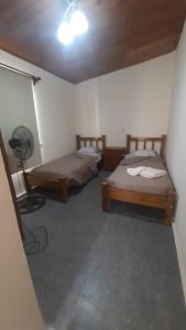 a room with two beds and a fan at Posada Mis Padres in Godoy Cruz