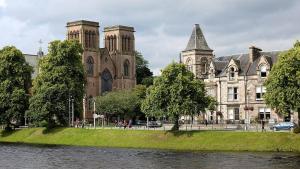 un gran edificio con un río delante de él en The 'Fairy Hill' Apartment, en Inverness