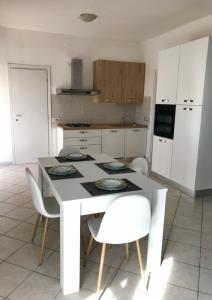 una cucina con tavolo bianco e sedie bianche di Attico centralissimo e vicino al mare ad Alghero