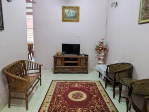 uma sala de estar com televisão, cadeiras e um tapete em Aryani Homestay em Kampong Kelemak