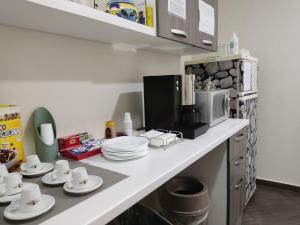 a kitchen counter with cups and plates and a microwave at Civico 83 in Reggio di Calabria