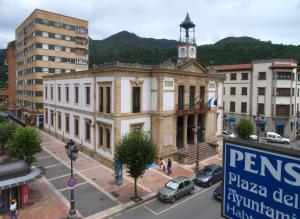 un antiguo edificio con una torre de reloj en una ciudad en Pensión Plaza del Ayuntamiento, en Cangas de Onís