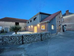 a house with a stone wall next to a building at Gîte le belloy'Zo in Belloy sur Somme