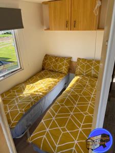 - 2 lits dans une petite chambre avec fenêtre dans l'établissement Chapel St Leonards Caravan, à Chapel St. Leonards