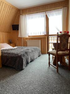 een slaapkamer met een bed, een stoel en een raam bij Willa Bałamutka in Zakopane