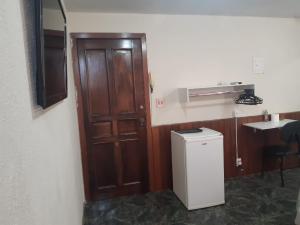 a kitchen with a wooden door and a small refrigerator at Pousada do Luquinhas in Brasília