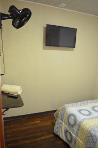 una camera da letto con un televisore appeso a un muro e un letto di #3 Private room Close to Airport a Alajuela