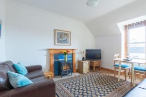 ein Wohnzimmer mit einem Sofa, einem Tisch und einem TV in der Unterkunft The 'Fairy Hill' Apartment in Inverness
