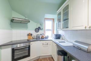 cocina con armarios blancos y encimera en The 'Fairy Hill' Apartment, en Inverness