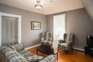 a living room with two chairs and a couch and a television at Hillcrest Hall Country Inn in Port Hood