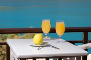 two glasses of orange juice and a lemon on a table at Pension Holidays in Vasiliki