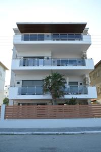 un edificio blanco con una palmera delante en Aqua Mare Luxury Apartments en Paralia Katerinis