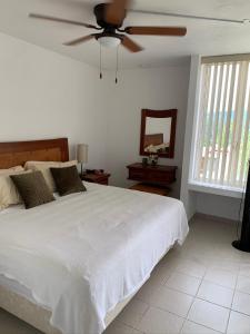 Schlafzimmer mit einem weißen Bett und einem Deckenventilator in der Unterkunft Casa en Oasis en Xochitepec in Chiconcuac