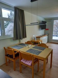 a dining room with a table and chairs and windows at Bayerwald Appartement in Sankt Englmar