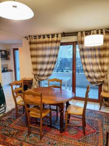 ein Esszimmer mit einem Tisch, Stühlen und einem Fenster in der Unterkunft Entre Lac d'Annecy et montagnes, golf et parapente à pieds in Talloires