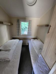 two beds in a small room with a window at Caravan Kensington 46 at Marton Mere Blackpool in Blackpool