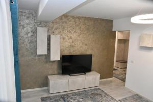 Una sala de estar con un televisor de pantalla plana en una pared. en SIF Residence, en Craiova