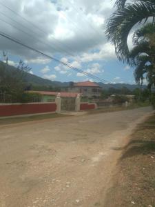 a dirt road with a house and a palm tree at Lovely 1-Bed Cottage in St catherine Jamaica in Ewarton