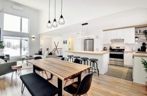uma cozinha e sala de estar com uma mesa de madeira e cadeiras em 100 Chemin des Ruisselets em Stoneham