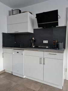 a kitchen with white cabinets and a black wall at Meet & Greet am Radfernweg E-Bike modern in Erfurt