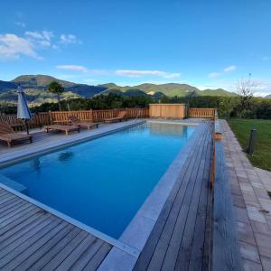 a swimming pool with a wooden deck and mountains in the background at Relax Guest Hause Marjanca in Rogaška Slatina