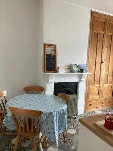 cocina con mesa, sillas y chimenea en Long Meadow Bakery, en Pembrokeshire