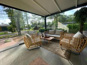 a screened in porch with a couch and chairs at Casa 2234 op camping de Schatberg in Sevenum