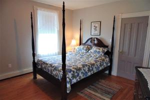 Schlafzimmer mit Himmelbett und Fenster in der Unterkunft Hillcrest Hall Country Inn in Port Hood