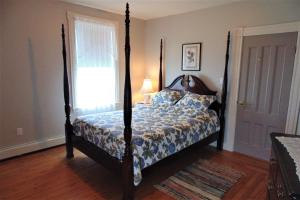a bedroom with a four poster bed with a window at Hillcrest Hall Country Inn in Port Hood