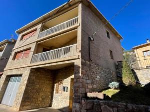 um grande edifício de tijolos com uma varanda em cima em LA CARA NORD , ALOJAMIENTO TURISTICO ,SALDES, A LOS PIES DEL PEDRAFORCA, apartamento em Saldés