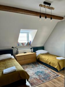 - une chambre mansardée avec 2 lits et une fenêtre dans l'établissement Apartament Katarzyny Puzyńskiej, à Jelenia Góra