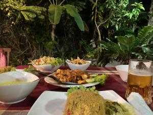 a table with plates of food and a glass of beer at Mallis Guesthouse in Habaraduwa
