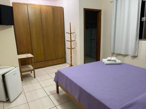 a bedroom with a purple bed and a cabinet at Hotel Regência in São Lourenço