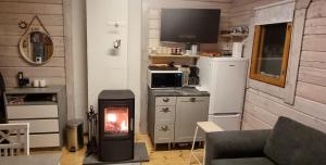 a living room with a fire in a stove at Mukava pieni 2-4h mökki min 2 vrk Saimaan rannalla, poreallas, puusauna, Wi-Fi, Smart TV, parivuode ja vuodesohva in Savonlinna