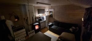 a living room with a couch and a kitchen at Mukava pieni 2-4h mökki min 2 vrk Saimaan rannalla, poreallas, puusauna, Wi-Fi, Smart TV, parivuode ja vuodesohva in Savonlinna