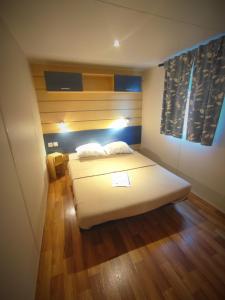 a bedroom with a white bed and wooden floors at Mobil-Home Cosy 5 personnes camping le Ried - Europapark in Boofzheim