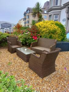 two wicker chairs and a table on a gravel patio at St. Hilary Guest House in Llandudno
