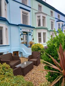 - un bâtiment bleu avec des chaises en osier devant dans l'établissement St. Hilary Guest House, à Llandudno