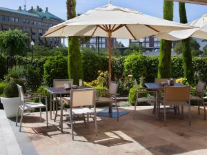 un patio con mesas y sillas bajo una sombrilla en Sercotel Valladolid en Valladolid