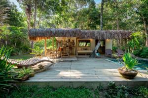 a wooden deck with a thatched roof in a garden at Vila Morena Altos de Itapororoca in Trancoso