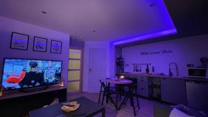 a living room with purple lighting and a tv and a kitchen at Mille et une nuit, appartement classé 3 étoiles en RDC avec exterieur et parking in Dole