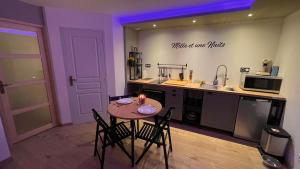 a kitchen with a table and some chairs and a counter at Mille et une nuit, appartement classé 3 étoiles en RDC avec exterieur et parking in Dole