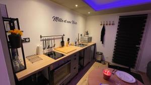 a kitchen with a counter with a sink and a microwave at Mille et une nuit, appartement classé 3 étoiles en RDC avec exterieur et parking in Dole