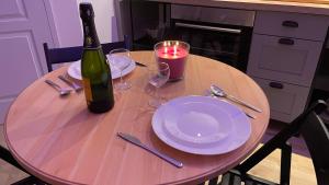 a table with a bottle of wine and a plate and candle at Mille et une nuit, appartement classé 3 étoiles en RDC avec exterieur et parking in Dole