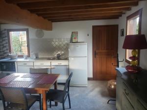 a kitchen with a table and a white refrigerator at LA PAGODE in Osmoy-Saint-Valery +5 photos