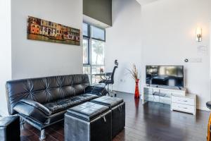 a living room with a leather couch and a tv at 1BR Furnished Apartment in Hollywood - Walk of Fame apts in Los Angeles