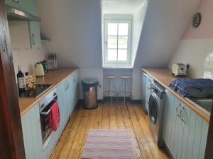 a kitchen with a sink and a washing machine at Argyll Mansions Penthouse in Oban