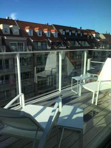 uma varanda com cadeiras e mesas num edifício em Ghibli - Duplex with parking em Knokke-Heist