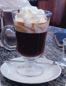 a glass cup of coffee with whipped cream on a table at La Cittadella10 in Turin